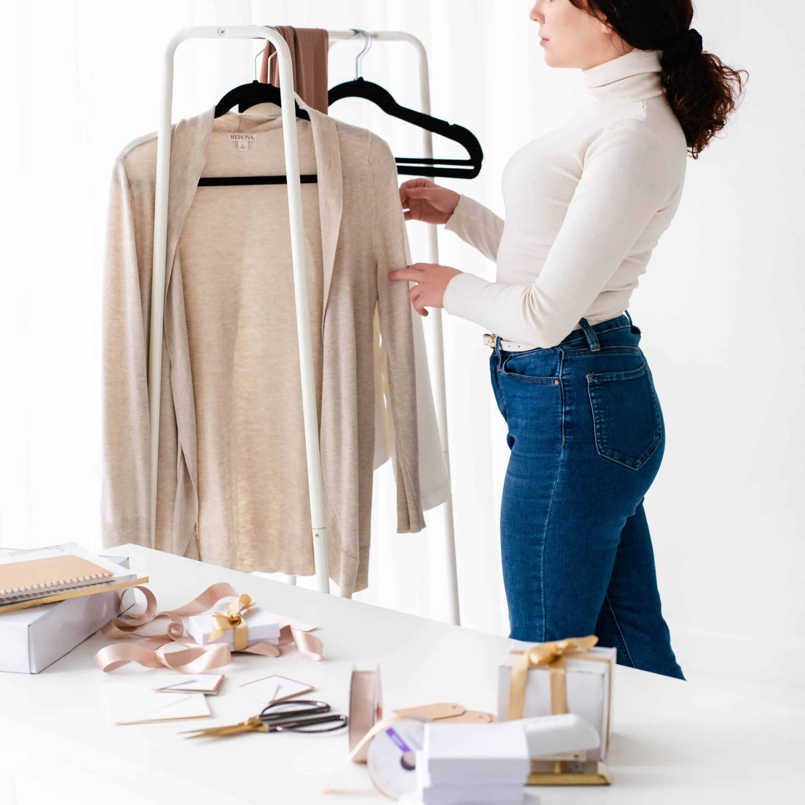 woman hanging clothes on rack while working at store